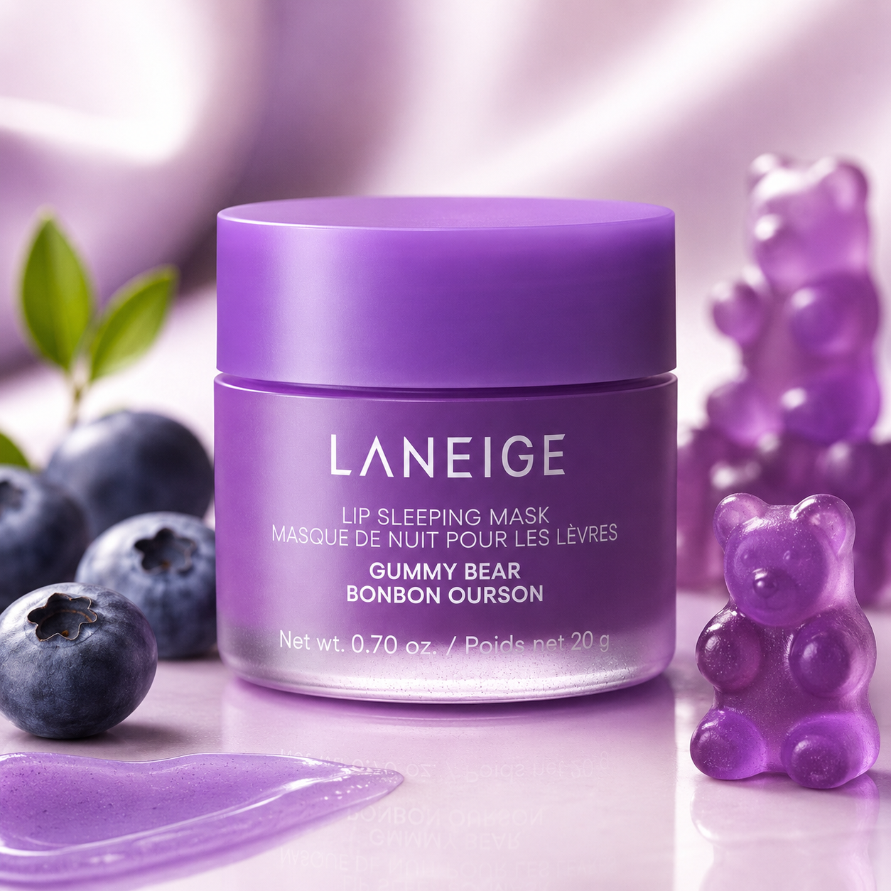 A purple jar of Laneige Lip Sleeping Mask sits among blueberries and gummy bear-shaped candies, showcasing its playful design and inviting texture. Soft lighting enhances the vibrant colors.
