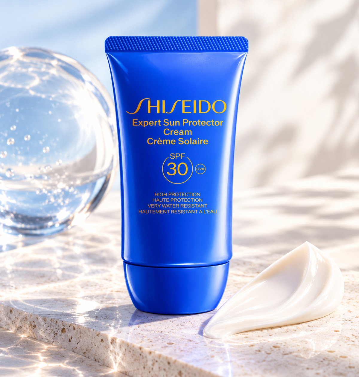 Shiseido Expert Sun Protector Cream SPF 30 in a vibrant royal blue tube with gold lettering, displayed on an elegant marble surface beside a smooth white cream texture and a transparent glass sphere. Premium, very water-resistant sunscreen offering high UVA protection in a fresh, luxurious skincare setting.