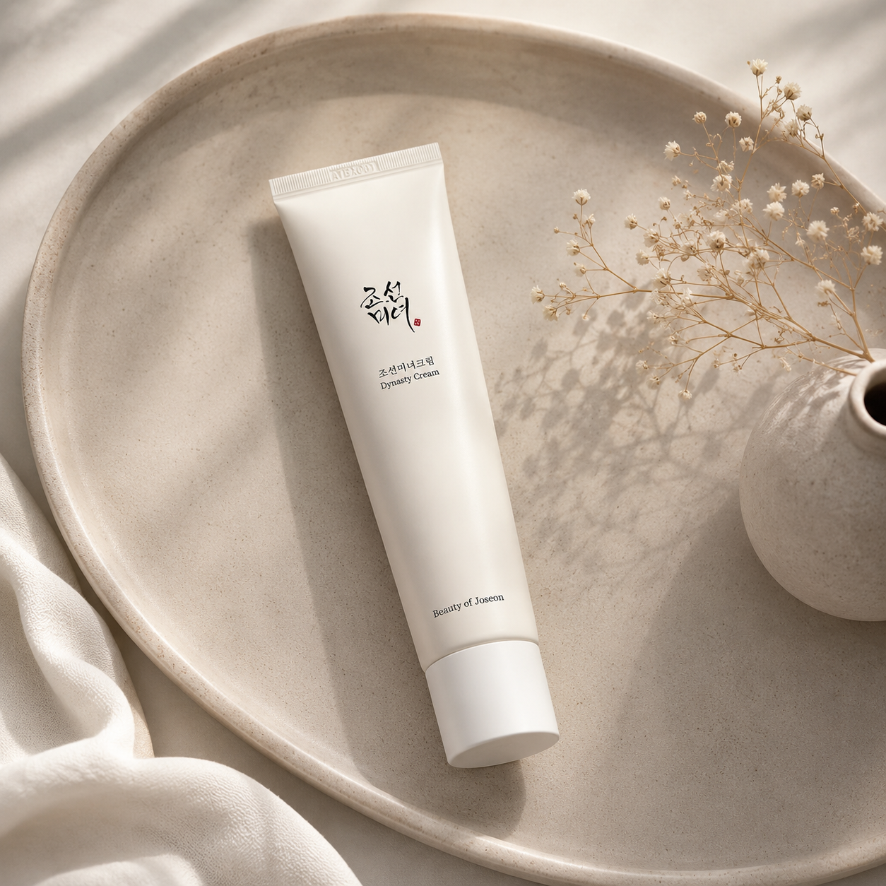 Beauty of Joseon Dynasty Cream 100ml on a beige plate with dried flowers and a vase